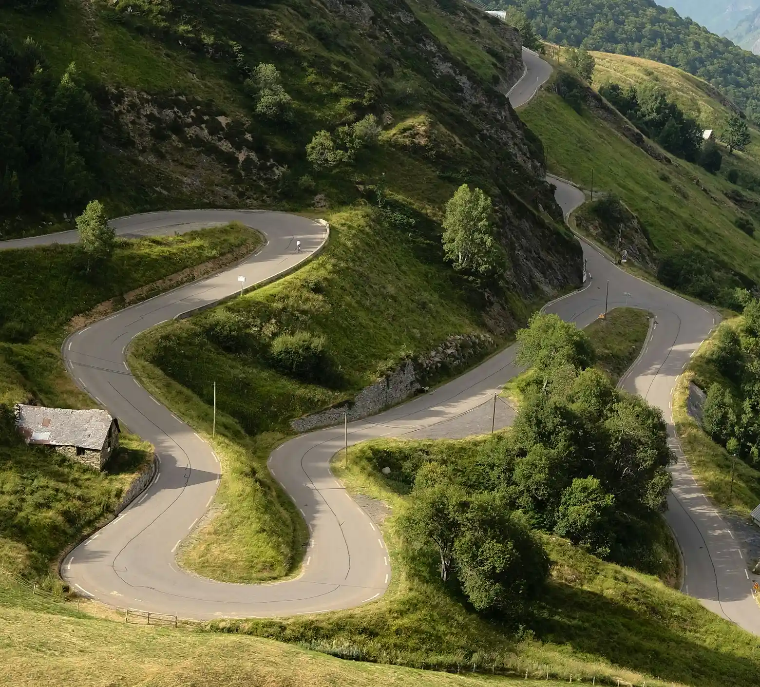 Serpentine road winding between the mountains covered in green.