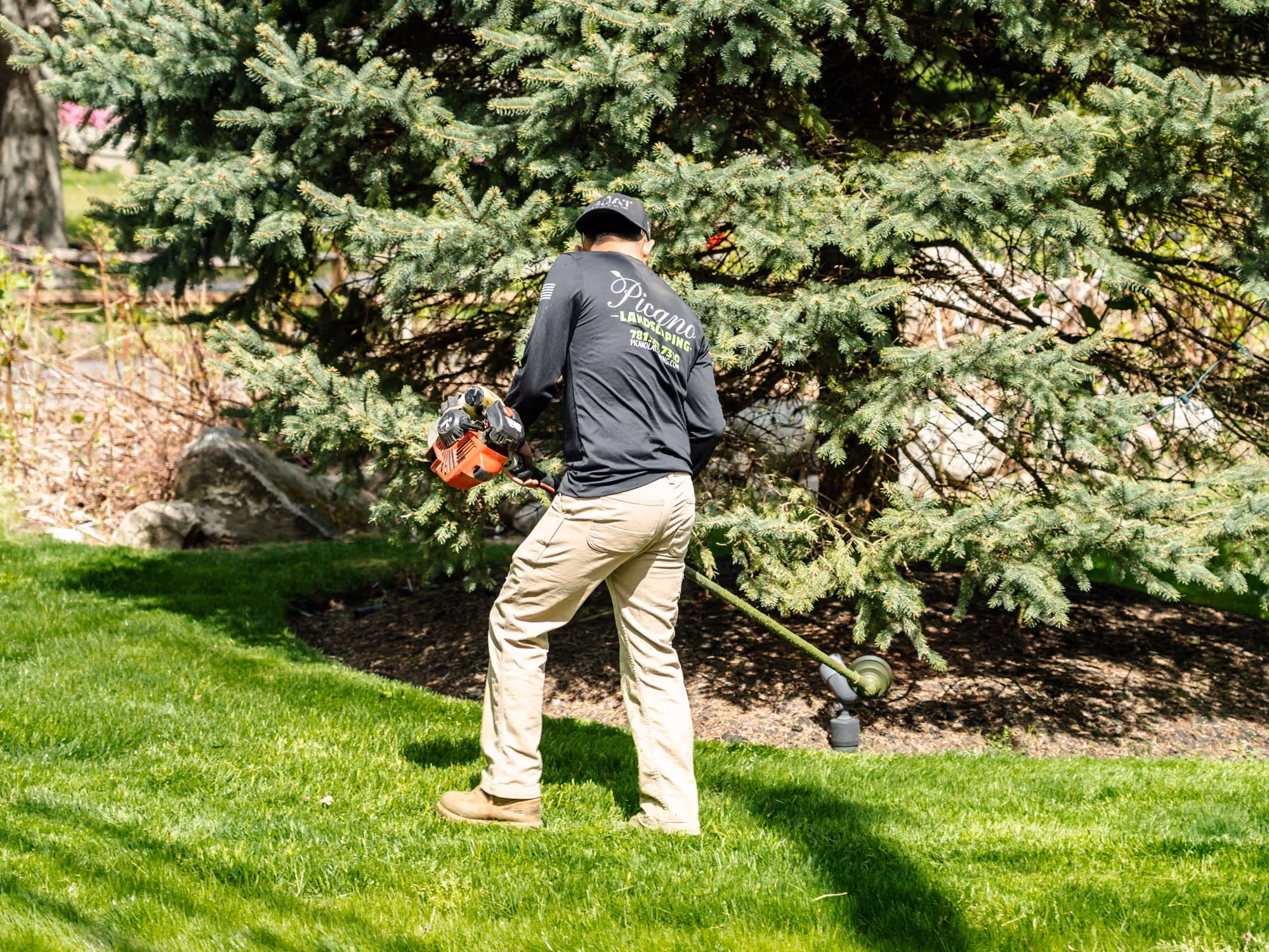 Freshly laid green sod bordered by stone edging next to a white house with a concrete walkway.