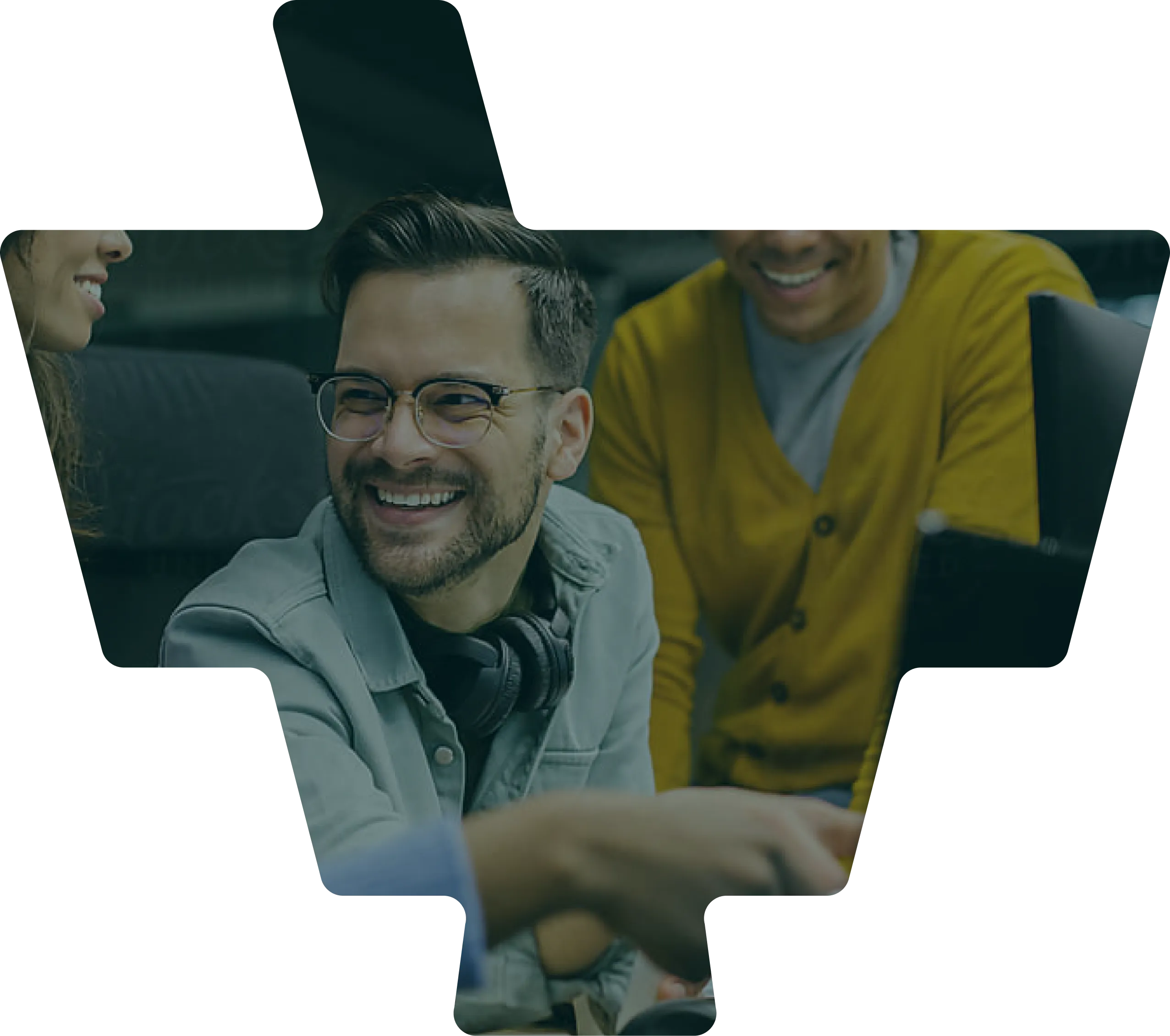 Three people smiling and engaging around a laptop in a casual work setting.