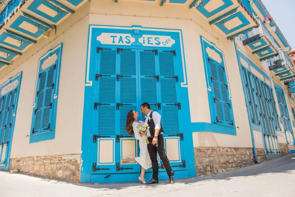 זוג חתונה מתנשק מול דלת כחולה מסורתית בקפריסין בחתונת יעד לזוג מישראל