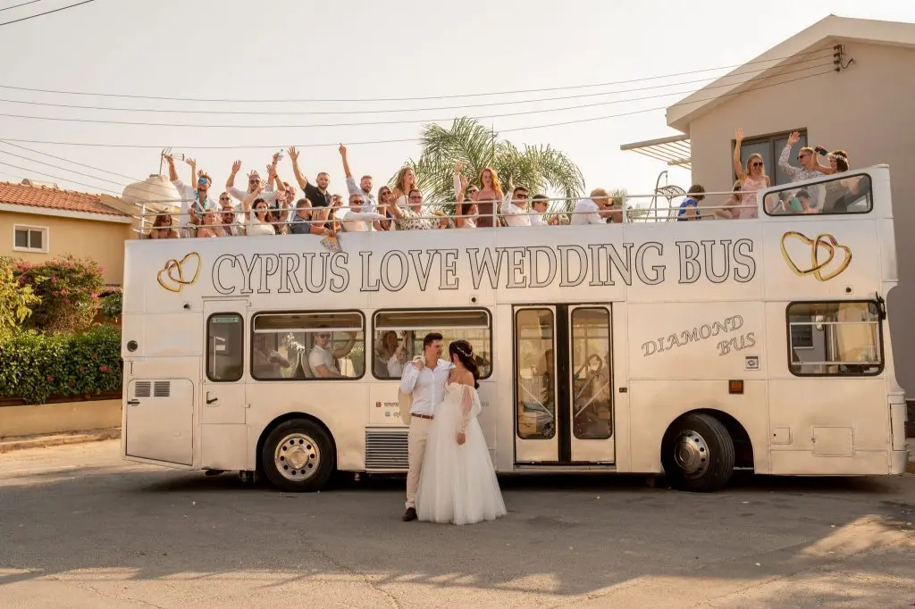 חתן וכלה עומדים מול אוטובוס החתונה Cyprus Love במהלך צילומי חתונה שמחים בקפריסין לזוג מישראל