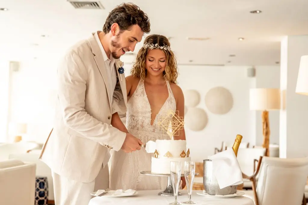 חתן וכלה חותכים עוגת חתונה באירוע אלגנטי באולם בקפריסין לזוג מישראל