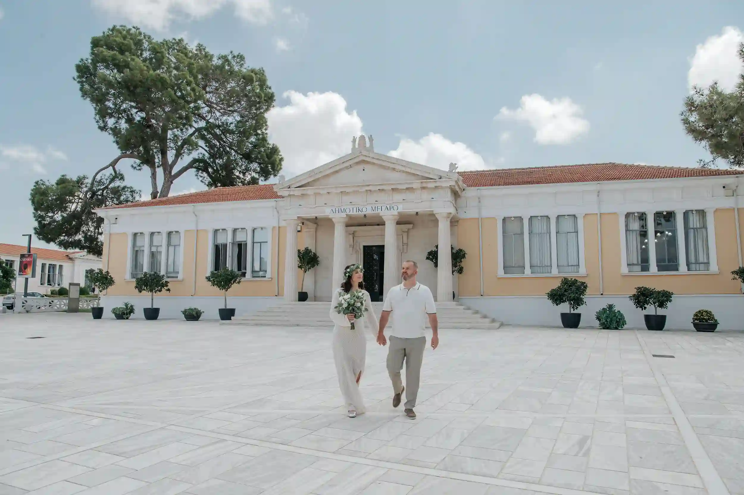 חתן וכלה הולכים יחד בחצר מבנה היסטורי בקפריסין במהלך חתונת יעד אלגנטית לזוג מישראל