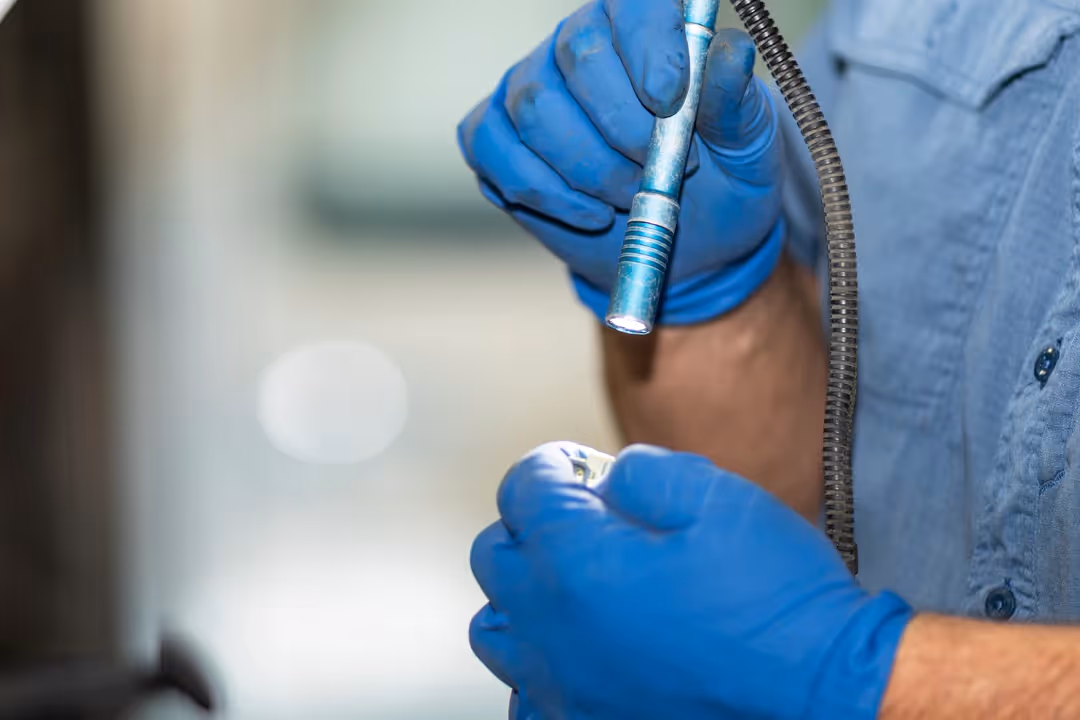 Technician wearing blue clothing and blue gloves inspecting truck parts