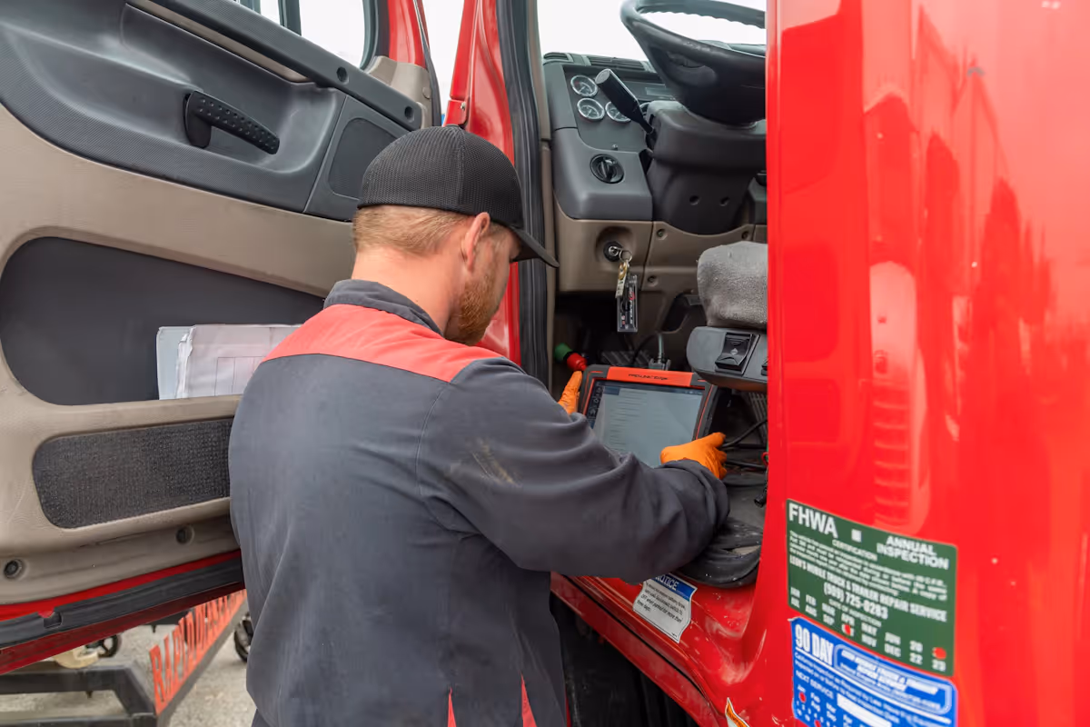 A truck technician running diagnostics on the roadside on a big semi truck