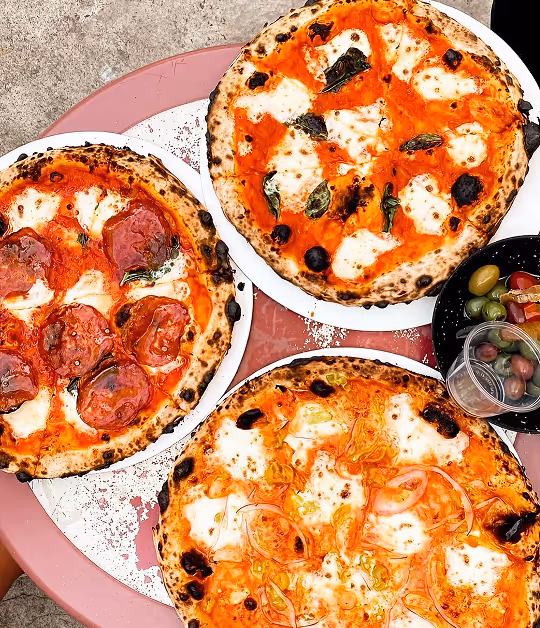 Variety of wood-fired pizzas on a table at Roberta’s Pizza restaurant.