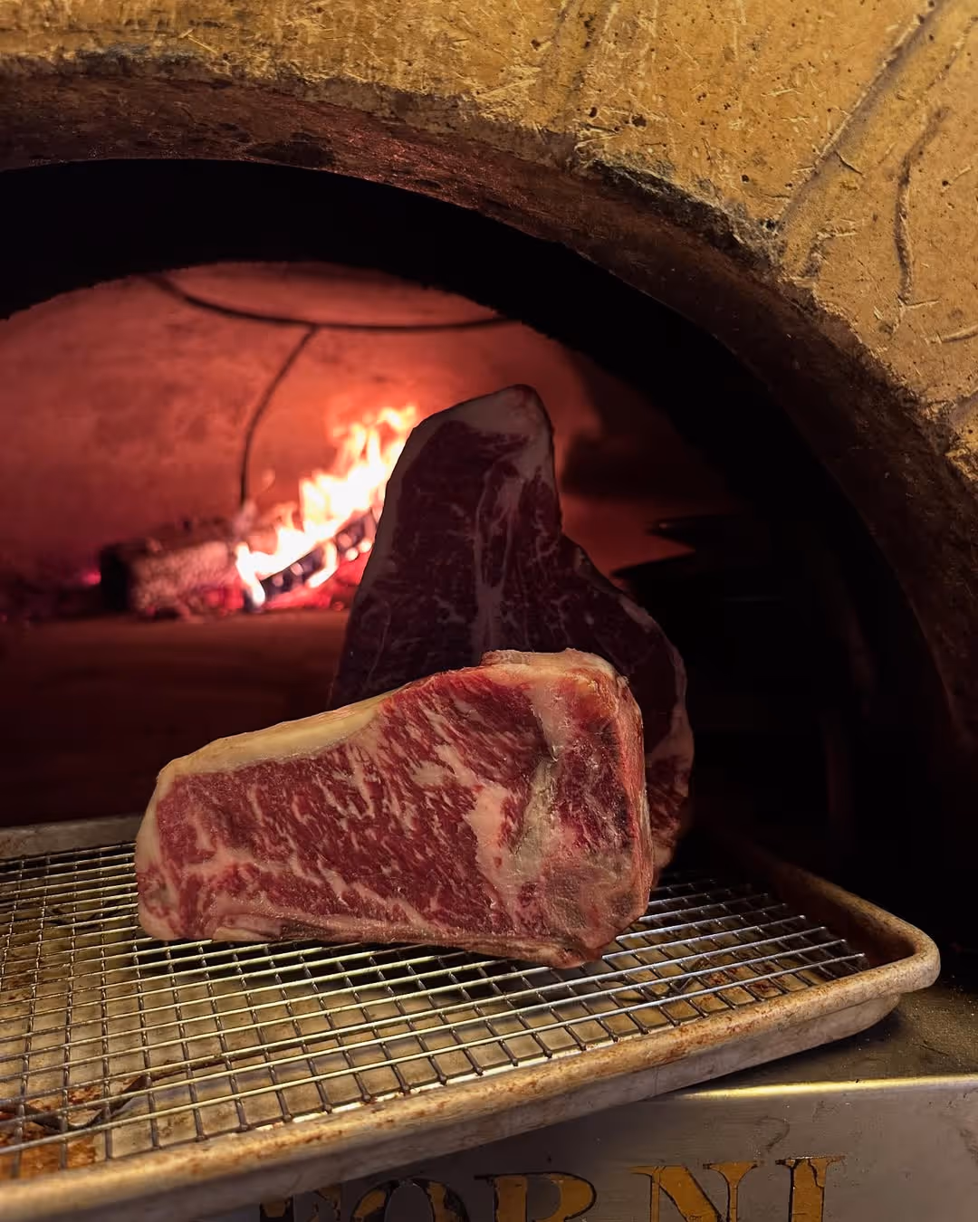 Thick cuts of marbled beef ready to be seared in the traditional wood-fired oven at Roberta’s Pizza restaurant.
