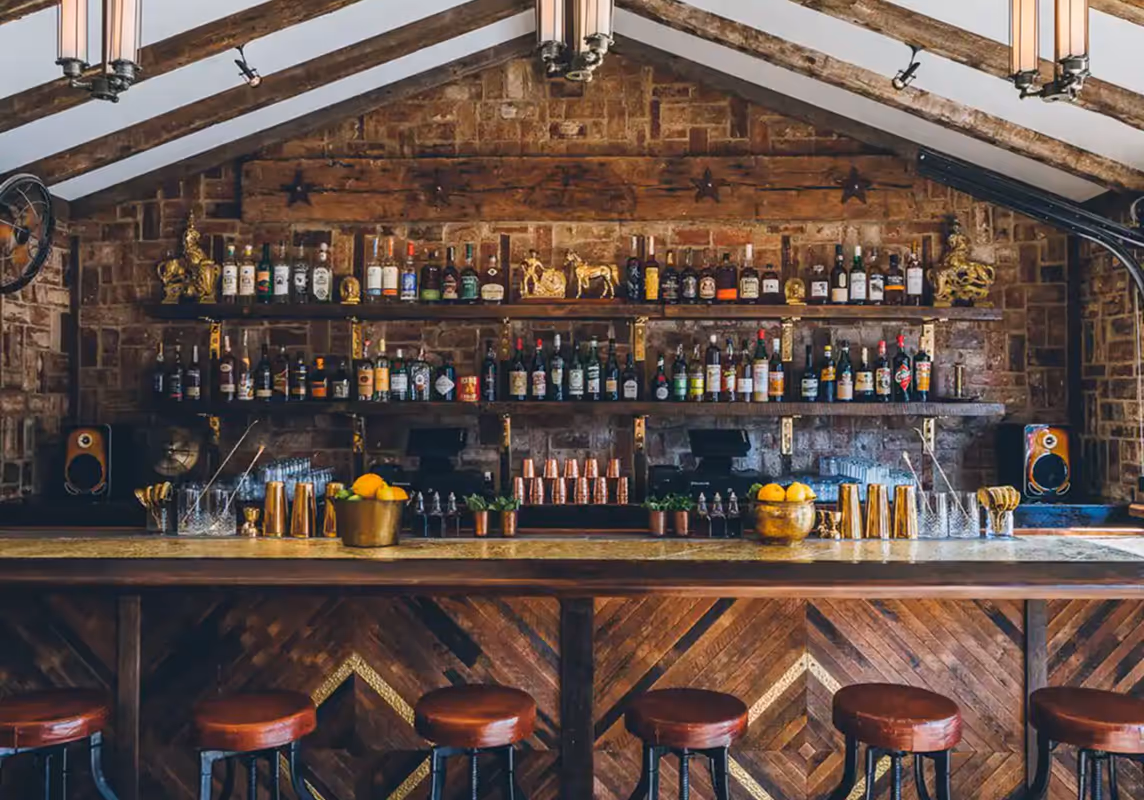 Rustic indoor bar at Roberta’s Pizza restaurant with wooden shelves and leather stools.