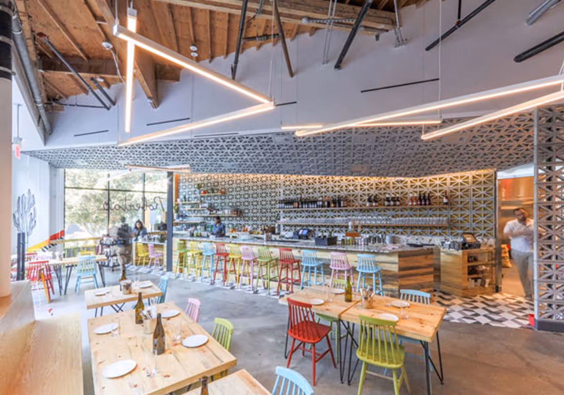 Spacious dining room at Roberta’s Pizza restaurant featuring designer lighting and communal tables.