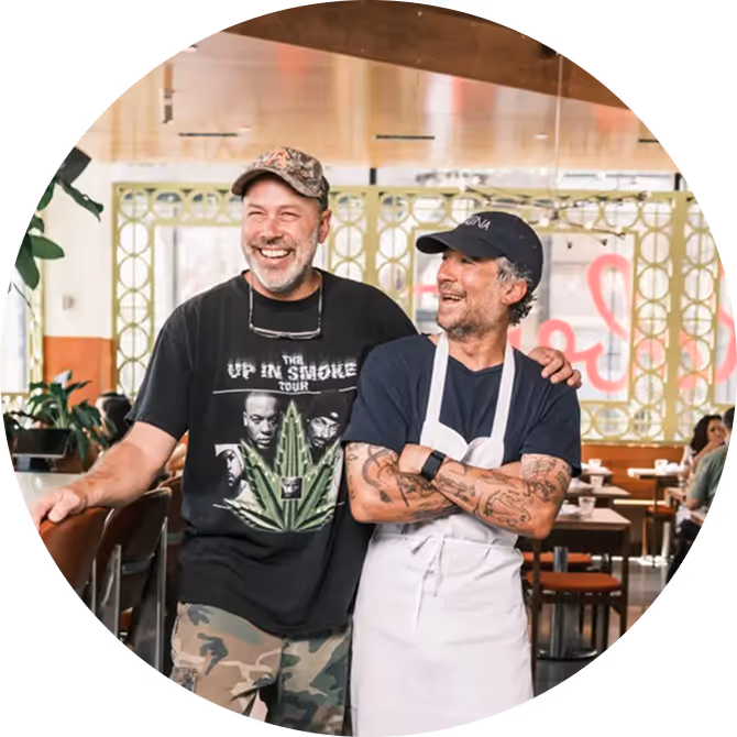 Co-founders and owners of Roberta’s Pizza restaurant smiling together in their dining room.