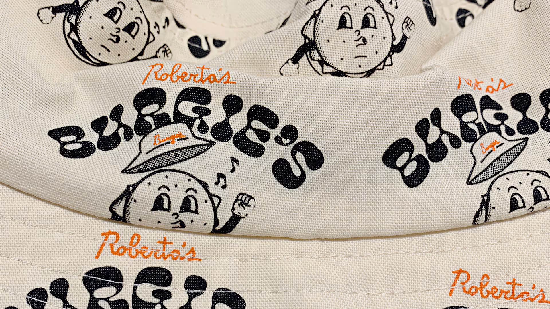Close-up of promotional apparel featuring fun retro illustrated characters for Roberta’s Pizza restaurant merchandise.