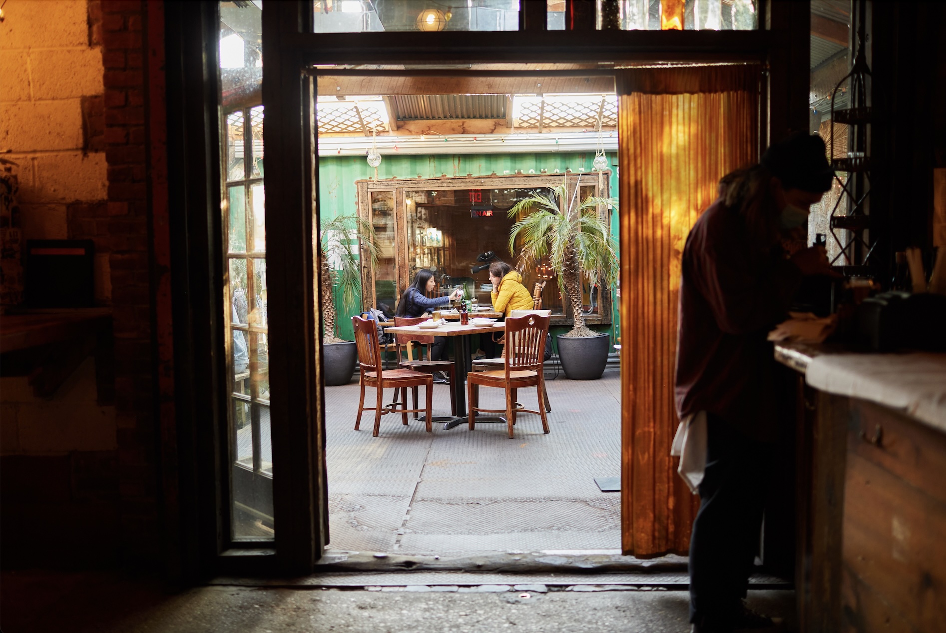 Rustic interior of Roberta’s Pizza restaurant showing the wooden bar area, chalkboard drink menu, and casual atmosphere.