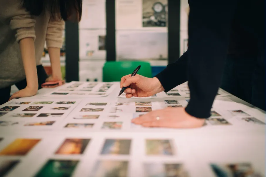 Hand mit Stift über ausgedruckten Storyboard-Bildern auf einem Tisch