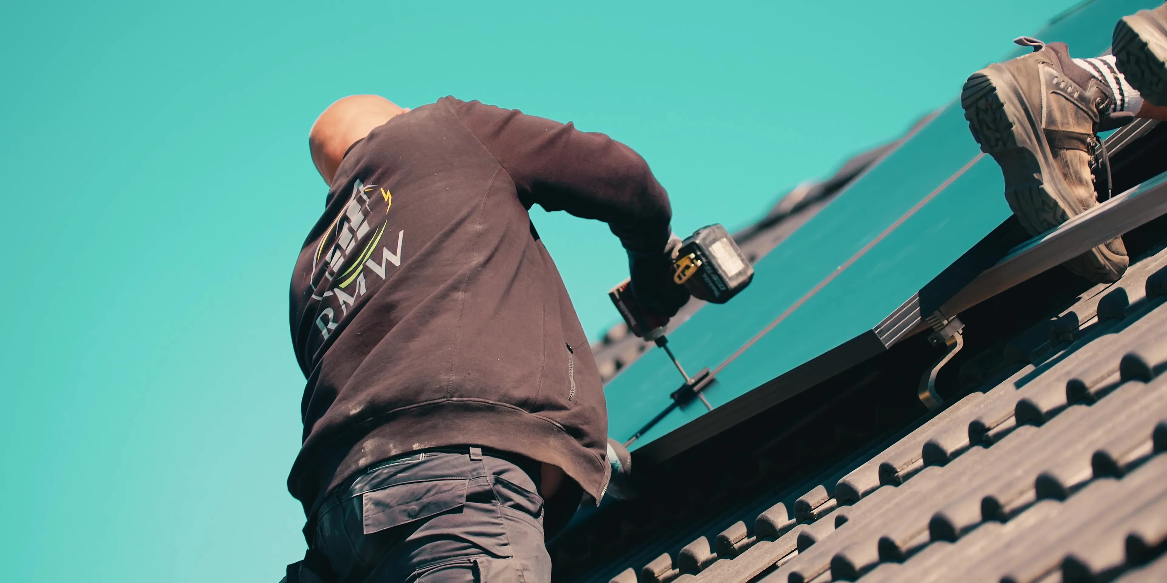 Handwerker bohrt bei der Montage von Solarmodulen auf einem Dach