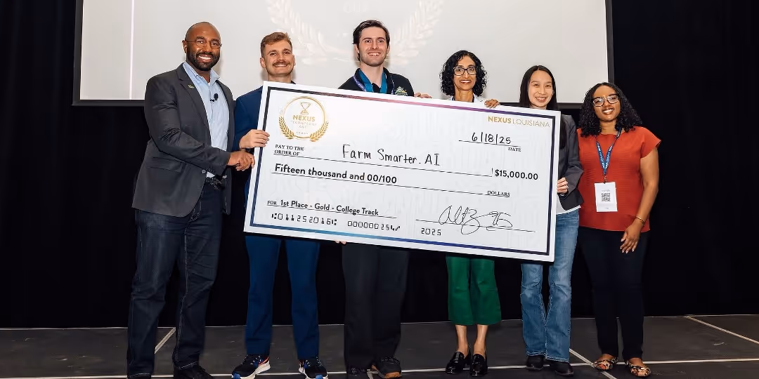 Two men in "L" hand gestures holding a $15,000 prize check on stage.