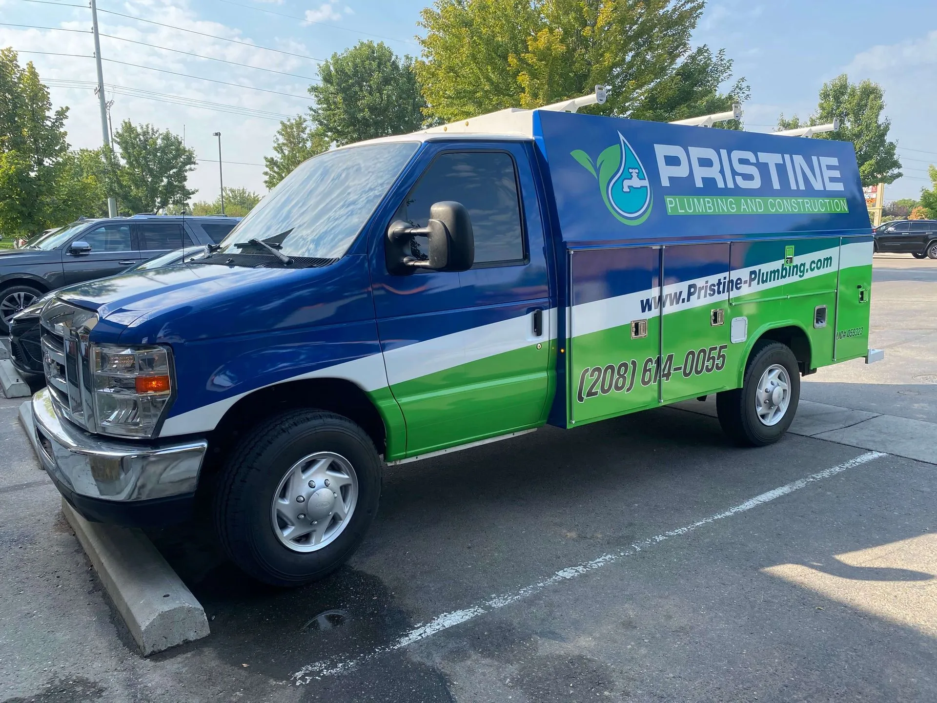 Blue and green Pristine Plumbing and Construction service van parked in a lot.
