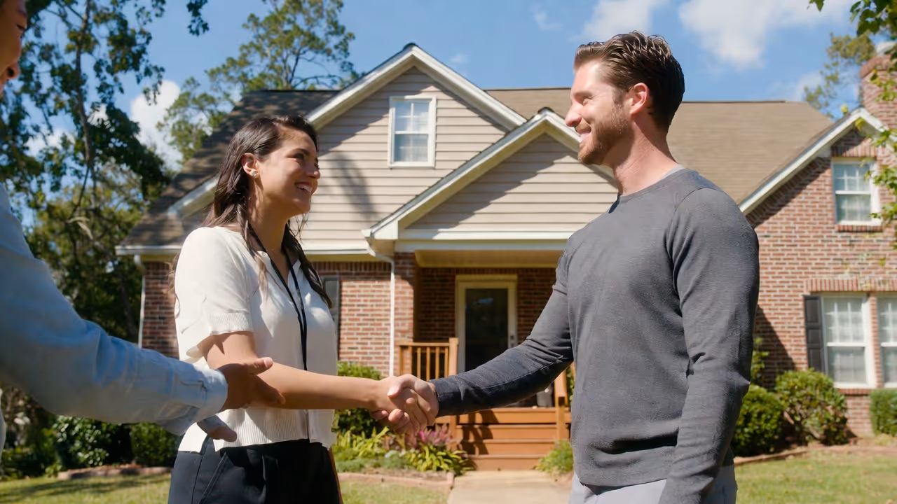 Real estate agent greeting happy couple outside North Georgia home.
