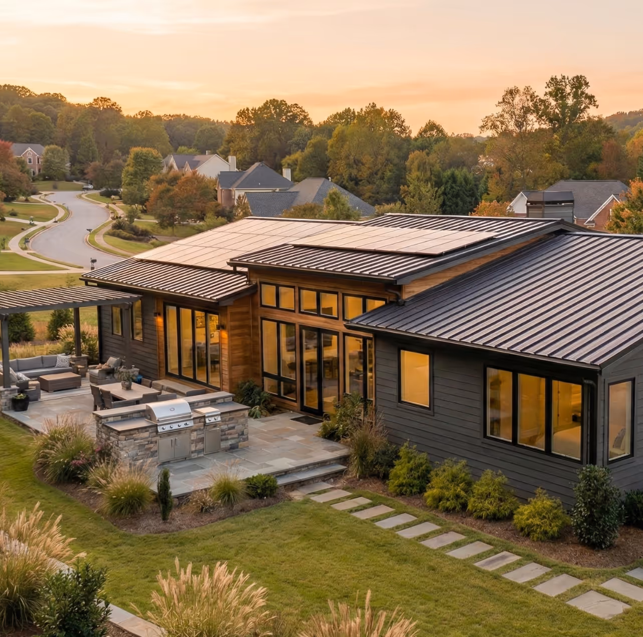 Modern ranch home in North Georgia with outdoor kitchen and metal roof at sunset.
