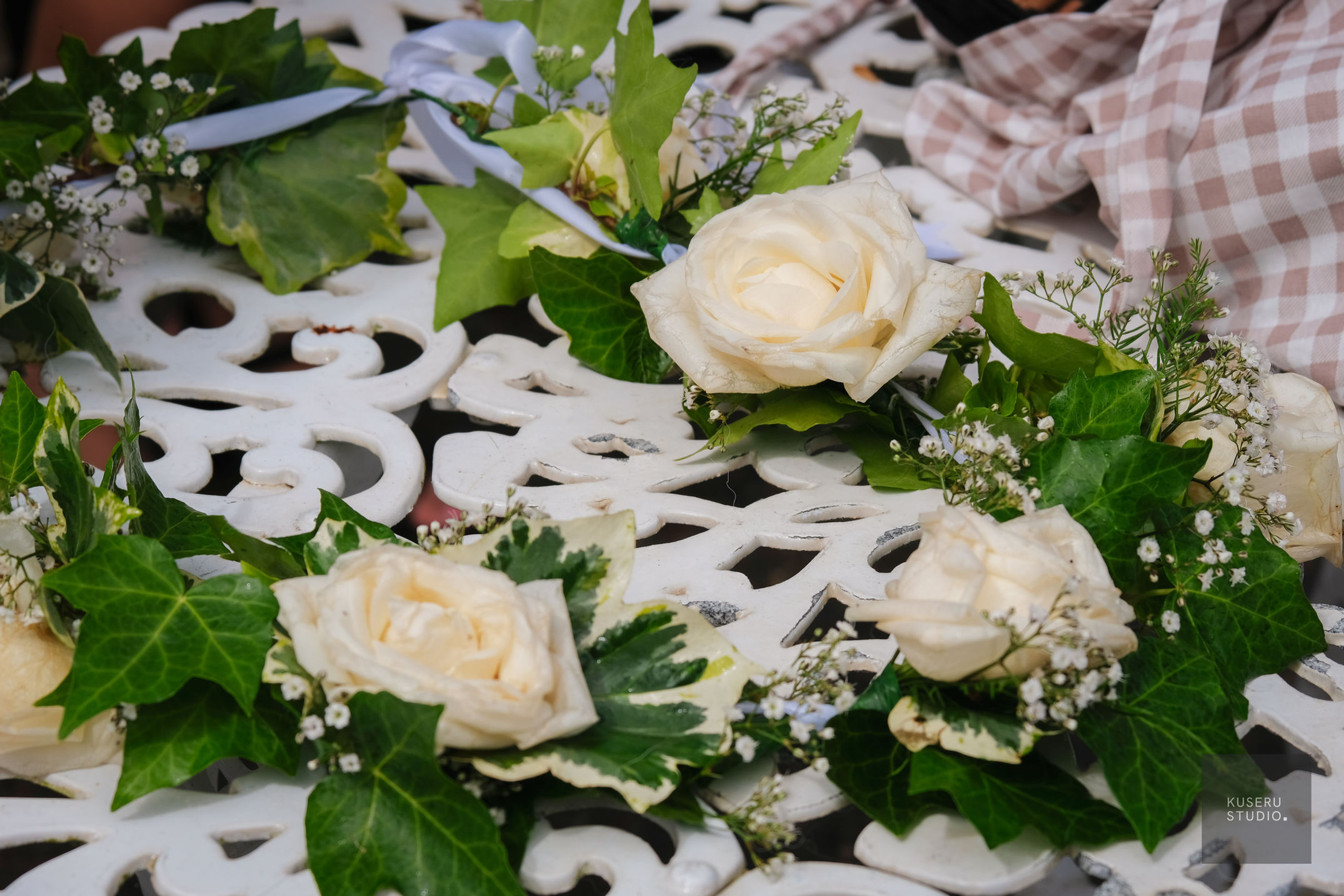 White roses and green ivy leaves arranged as floral engagement decorations on a white ornate table.