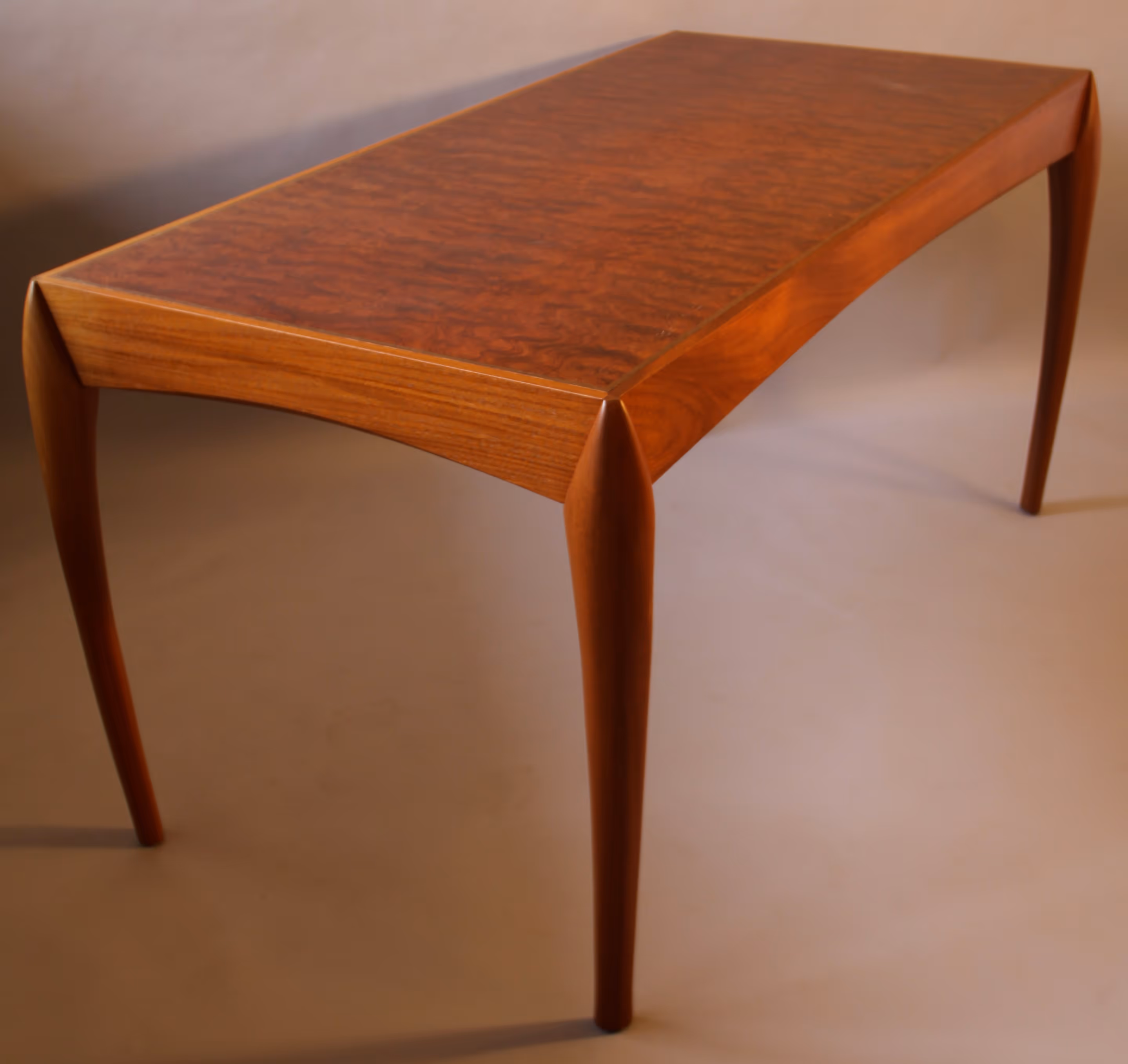 Elegant wooden table with a rich, polished surface and curved legs, set against a backdrop of vertical wooden planks.