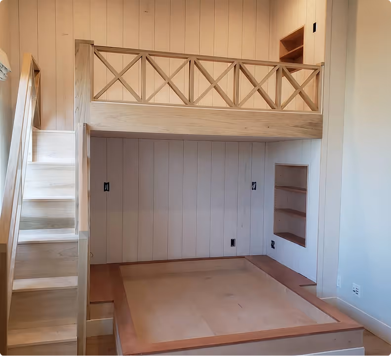 Custom wood loft bunk bed with X-pattern railing, built-in staircase with storage, shiplap walls, and recessed shelving below