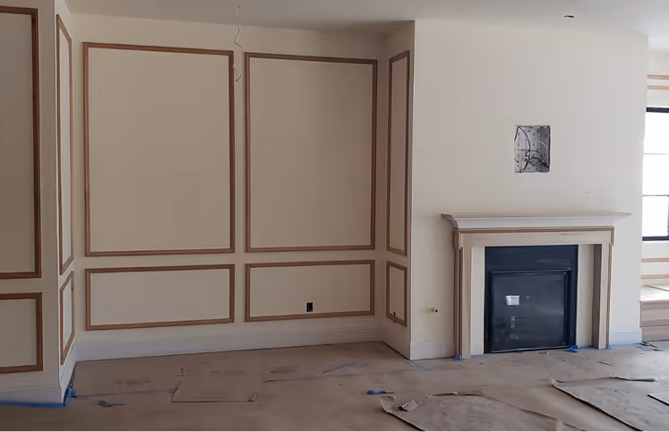 Unfinished room with wood paneling and a fireplace, featuring a large window and built-in shelves, ready for further work.