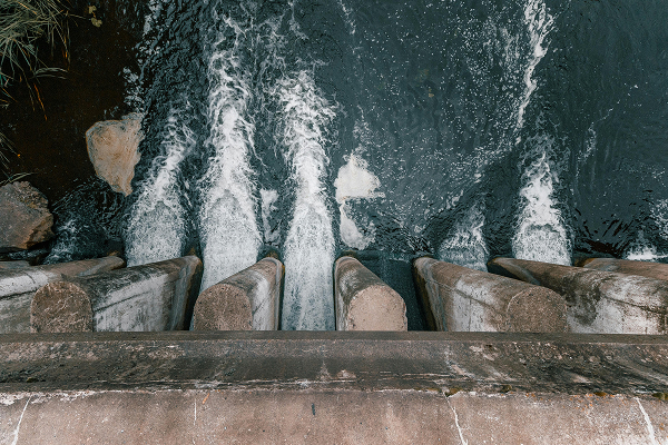 Water flowing rapidly through concrete barriers of a dam or water control structure.