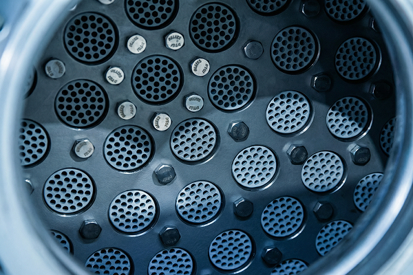 Close-up of the circular perforated metal plates and bolts inside an industrial membrane filter housing.