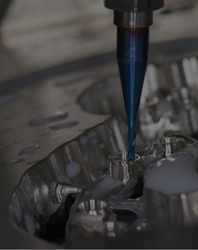 Close-up of a CNC machine drill cutting a shiny metal component.
