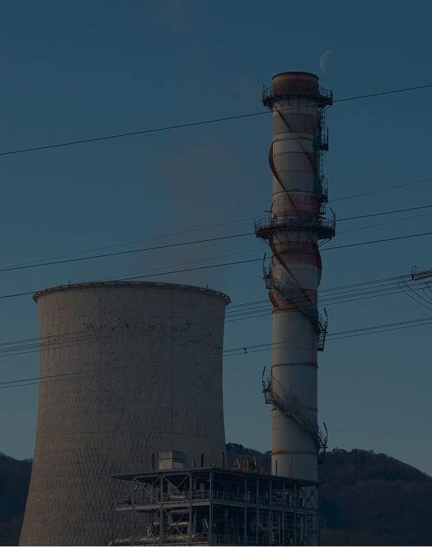 Industrial cooling tower and smokestack with metal staircases, set against a clear sky with visible moon.