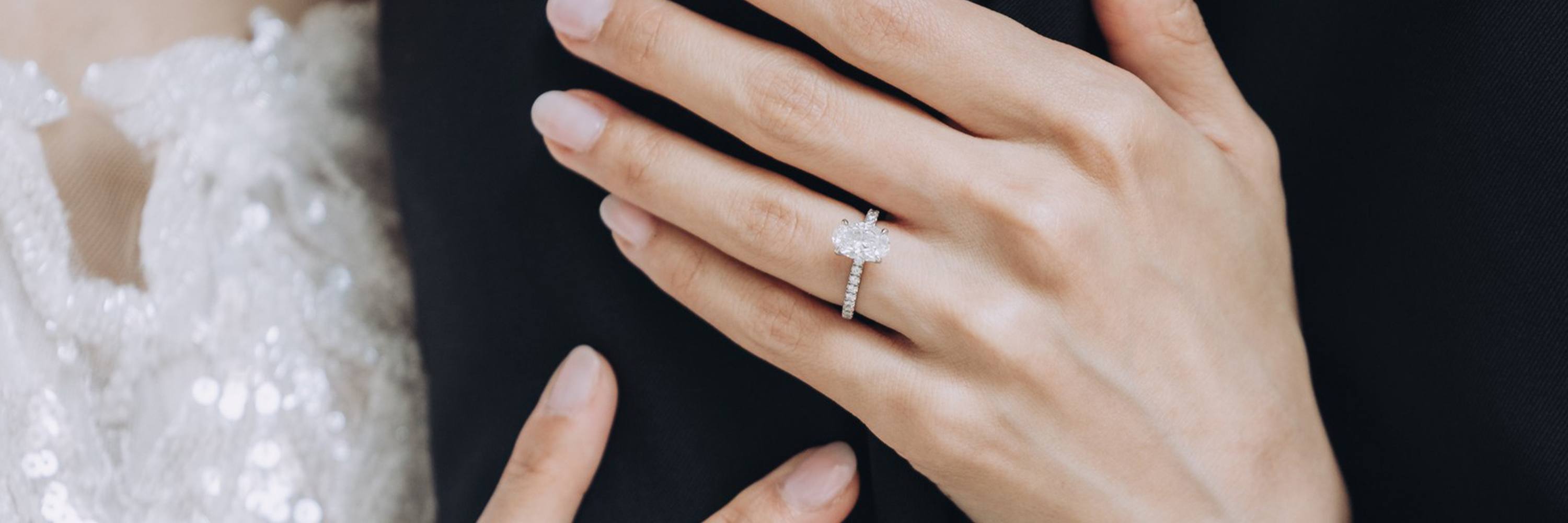 Person sitting cross-legged wearing a colorful jacket and orange pants against a purple background.