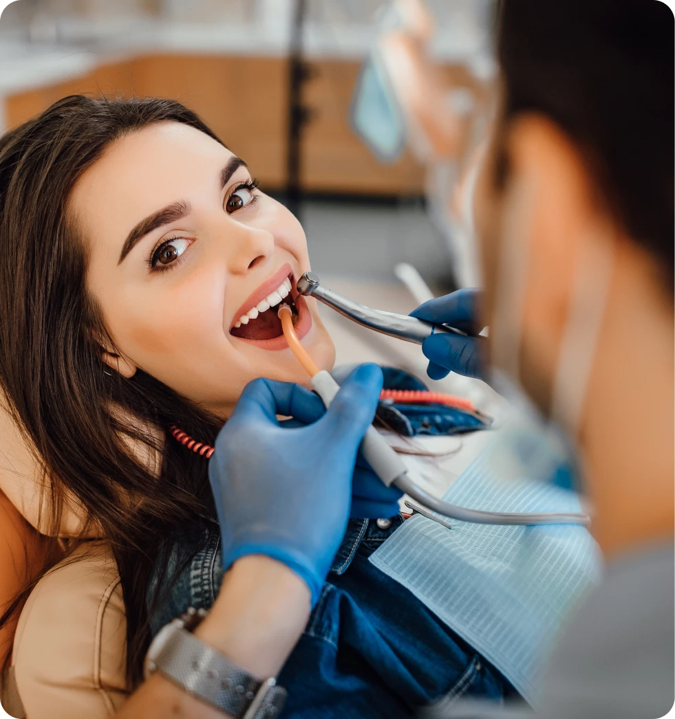 A woman getting her teeth brushed by a dentist.
