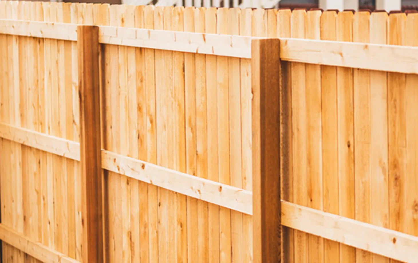 Close-up of a light wooden fence with vertical planks and horizontal support rails.