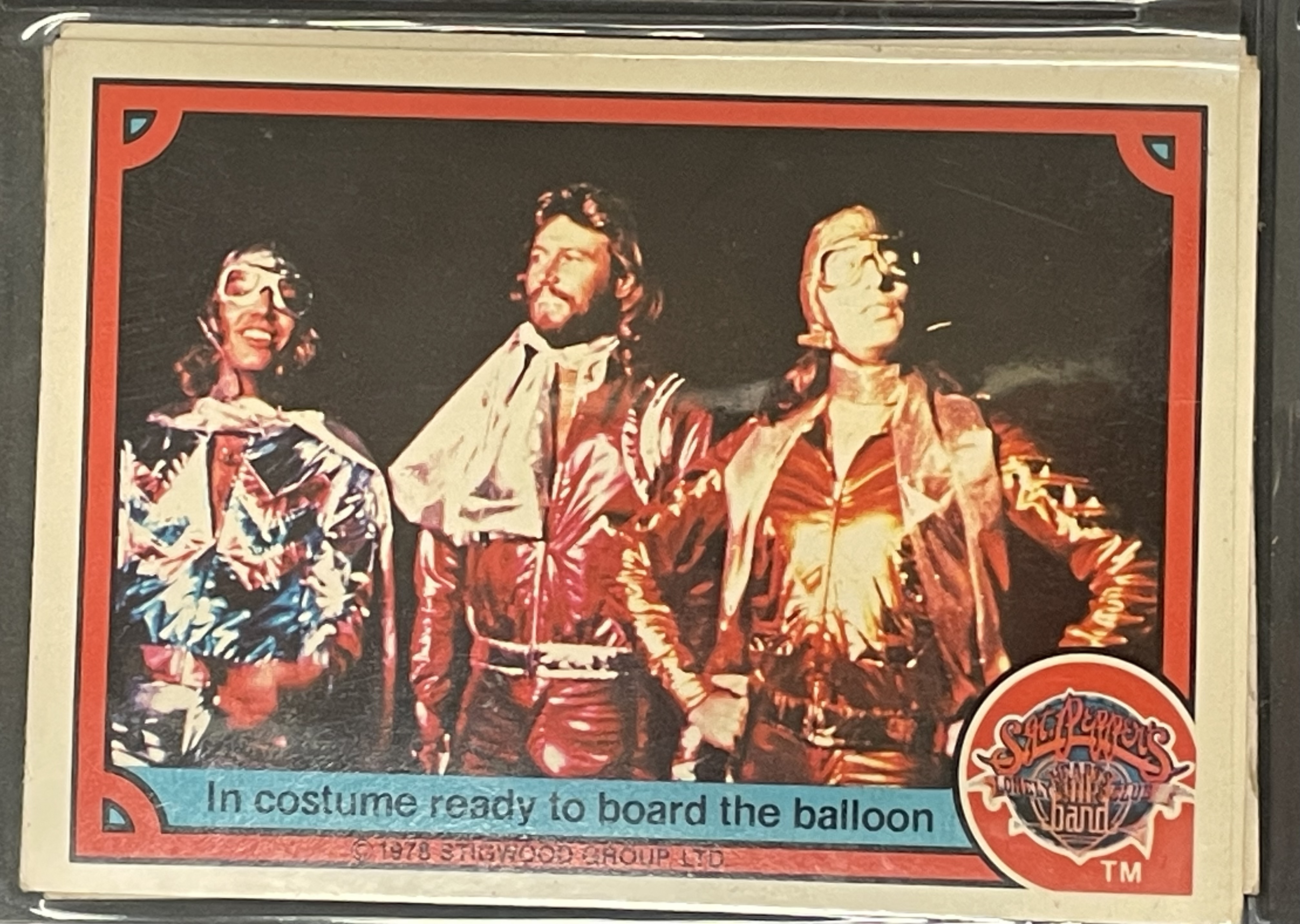 Costume sketch of a clown-like figure with a round beige torso, orange-striped sleeves, oversized purple pants, yellow gloves, and large yellow shoes.