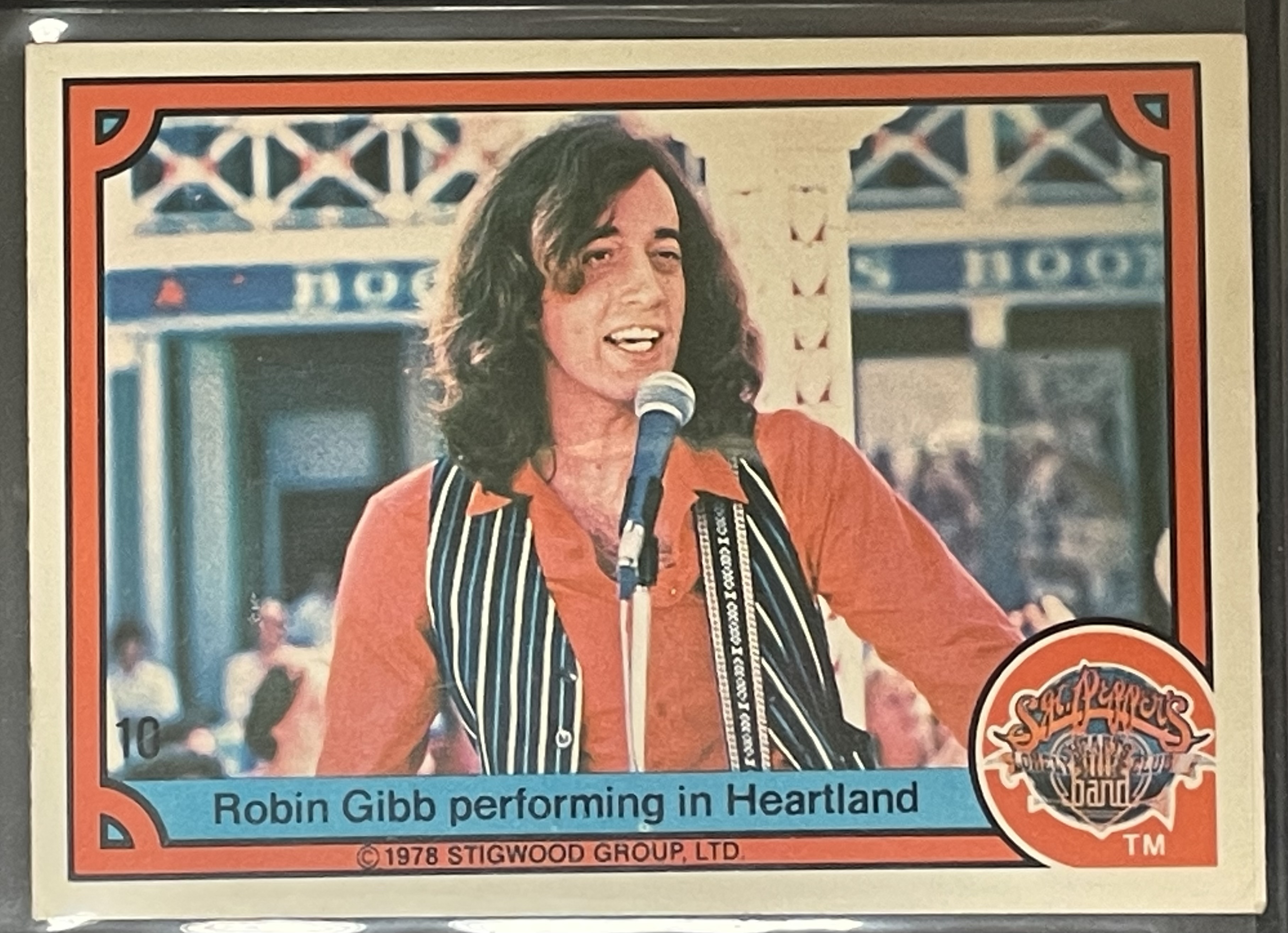 Costume sketch of a clown-like figure with a round beige torso, orange-striped sleeves, oversized purple pants, yellow gloves, and large yellow shoes.