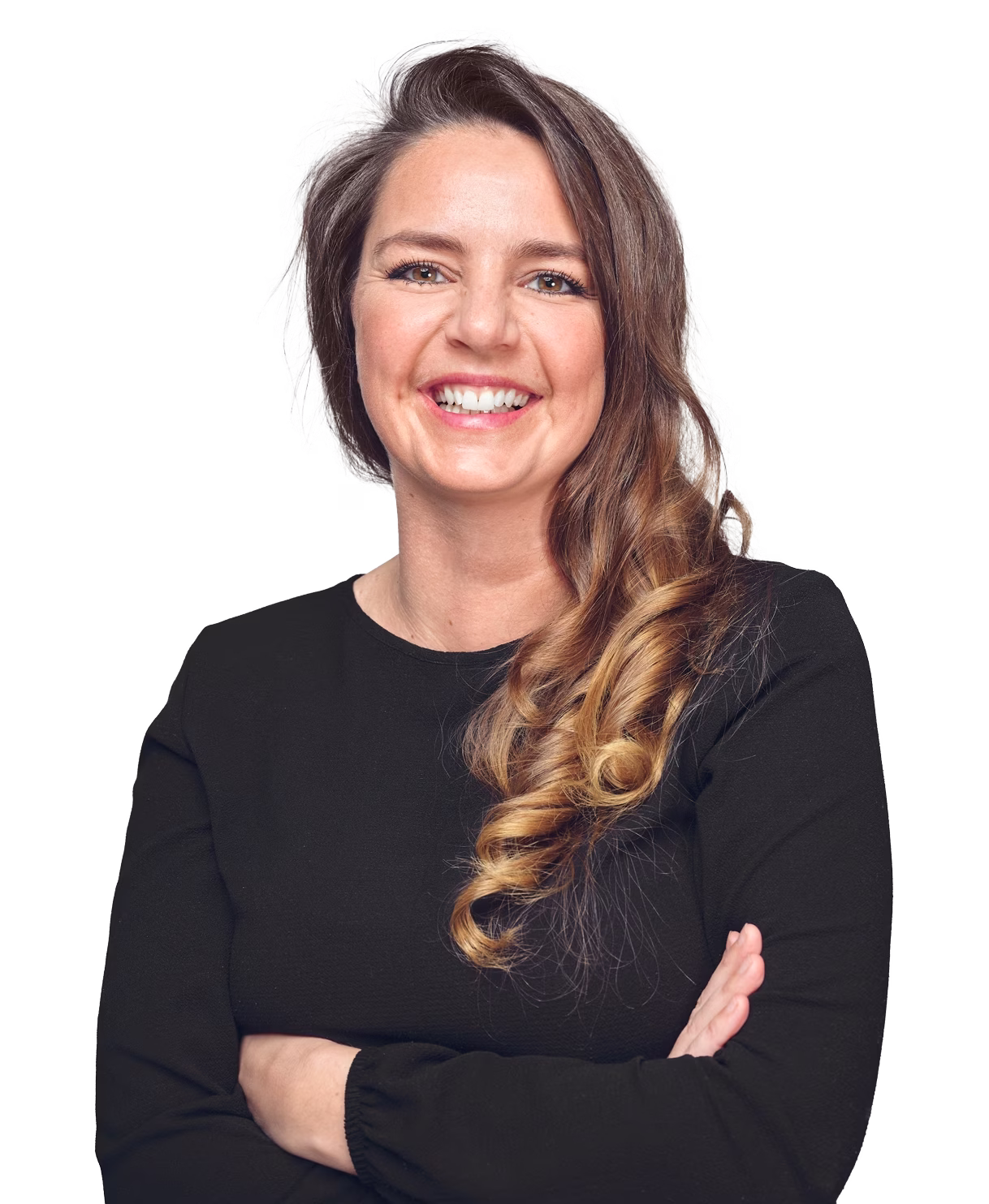 Lächelnde Frau mit langen, lockigen Haaren trägt schwarzen Pullover und hat die Arme verschränkt.