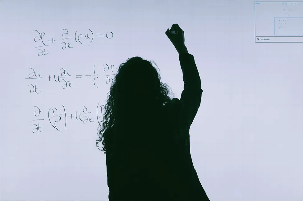 Een foto van een vrouw die een algebra formule op een bord schrijft.