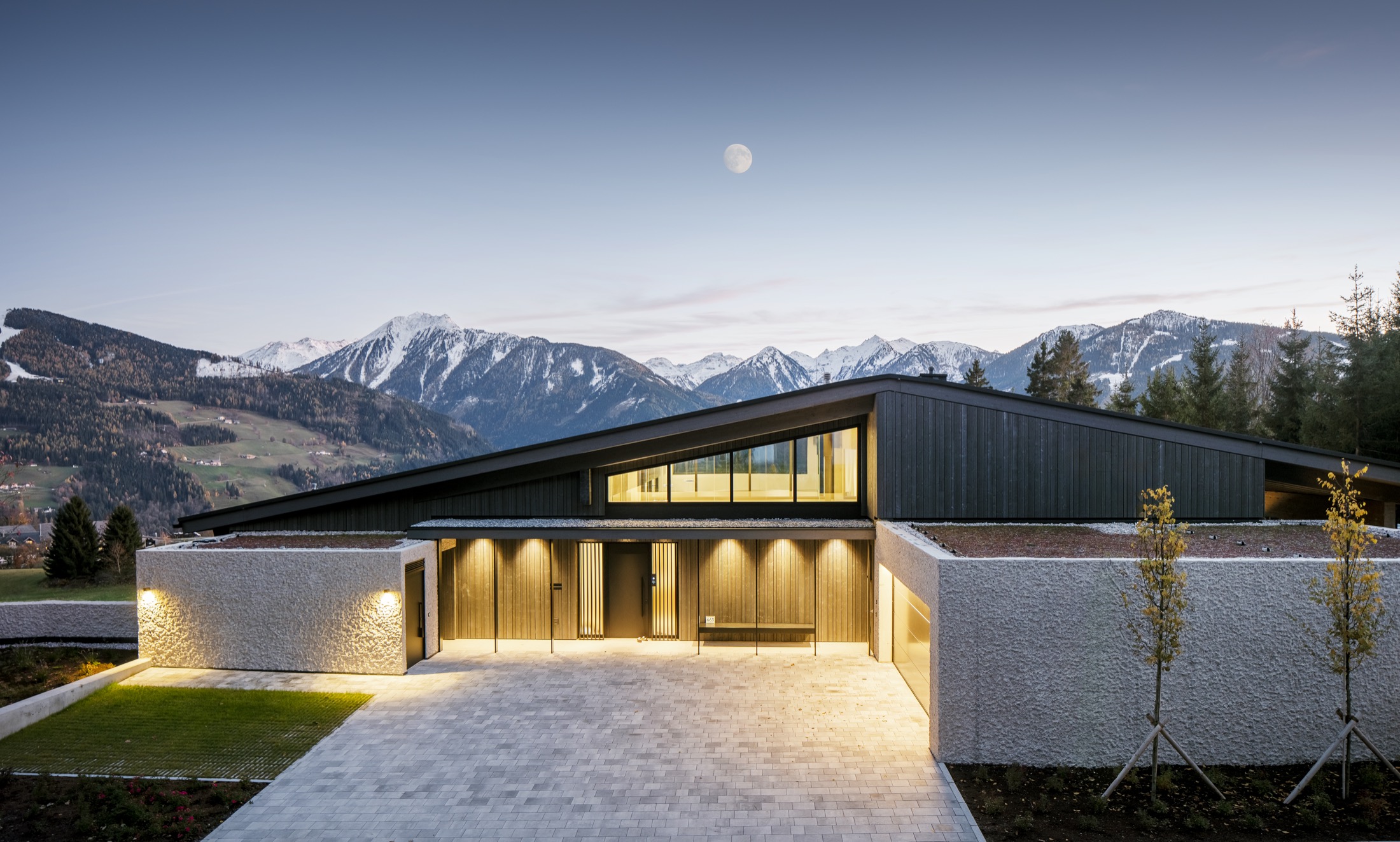 Wohnhaus bei Dämmerung mit beleuchtetem Entree und Mond