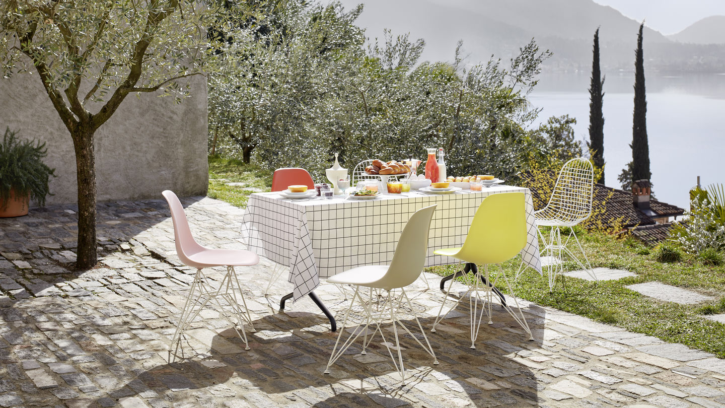 Vitra Eames Plastic Side Chairs am gedeckten Tisch im Freien – Design-Klassiker bei architare erleben