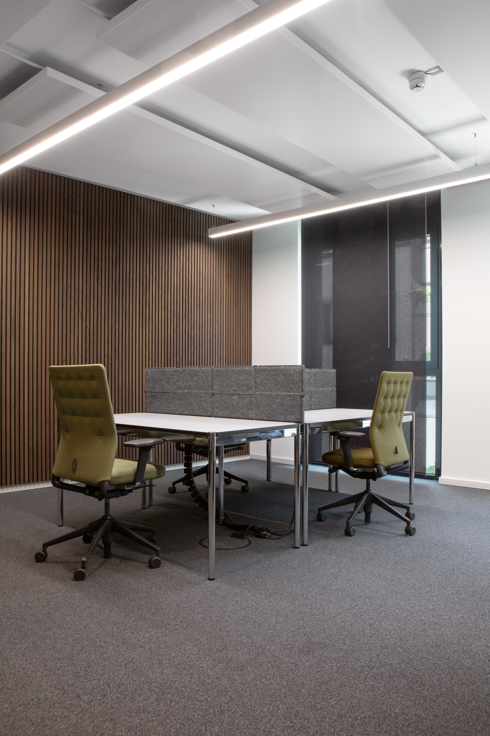 Arbeitsplätze mit Vitra ID Chair vor Holzlamellen und linearen Leuchten
