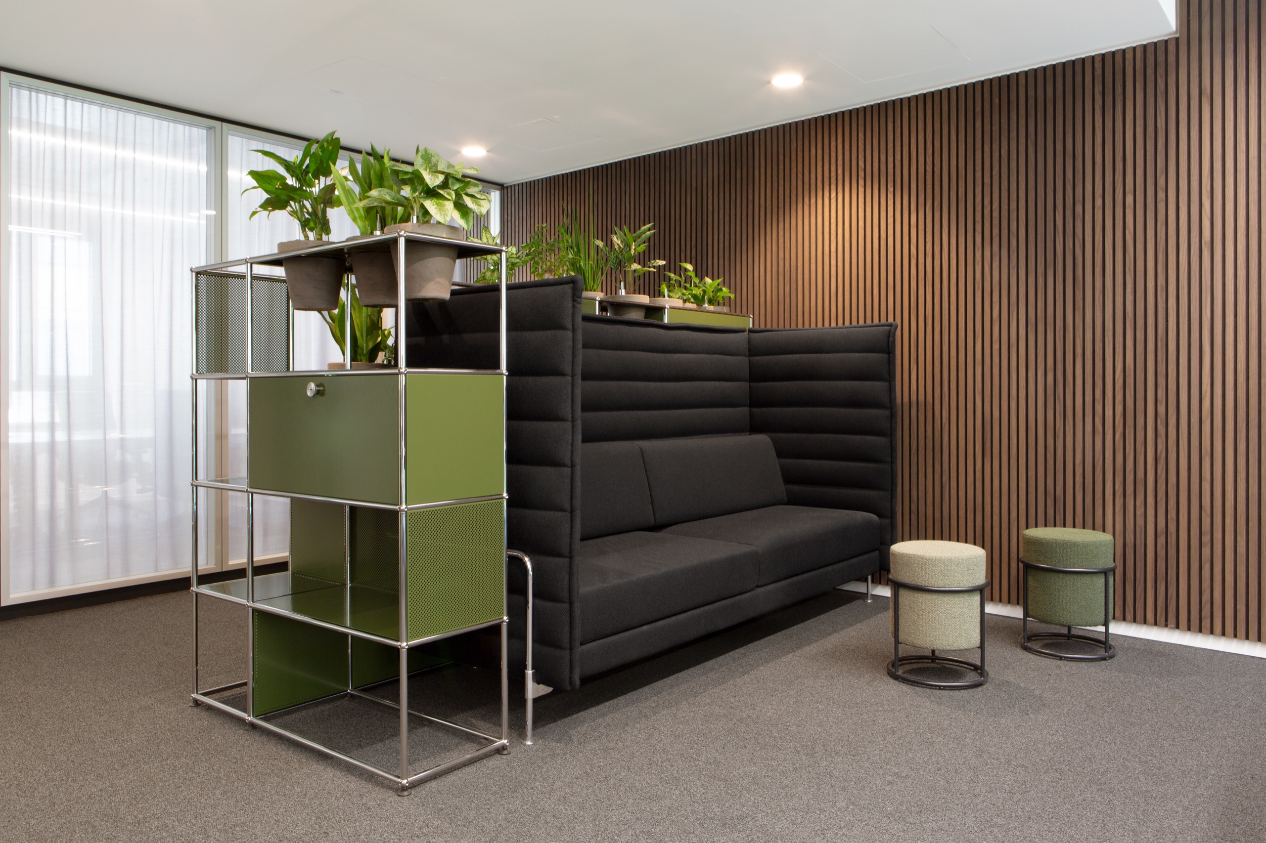 Olivgrünes USM Haller Regal als Pflanzenträger neben Vitra Alcove Sofa vor Holzlamellen