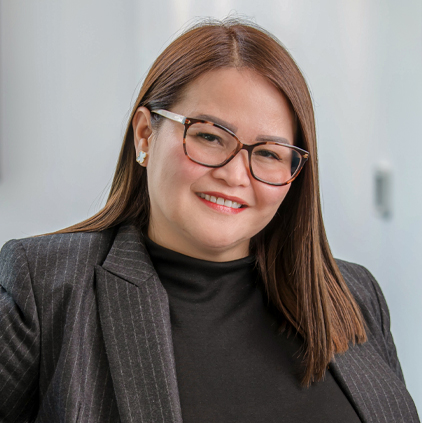 Smiling woman with straight brown hair, wearing glasses, a black top, and a pinstriped blazer.