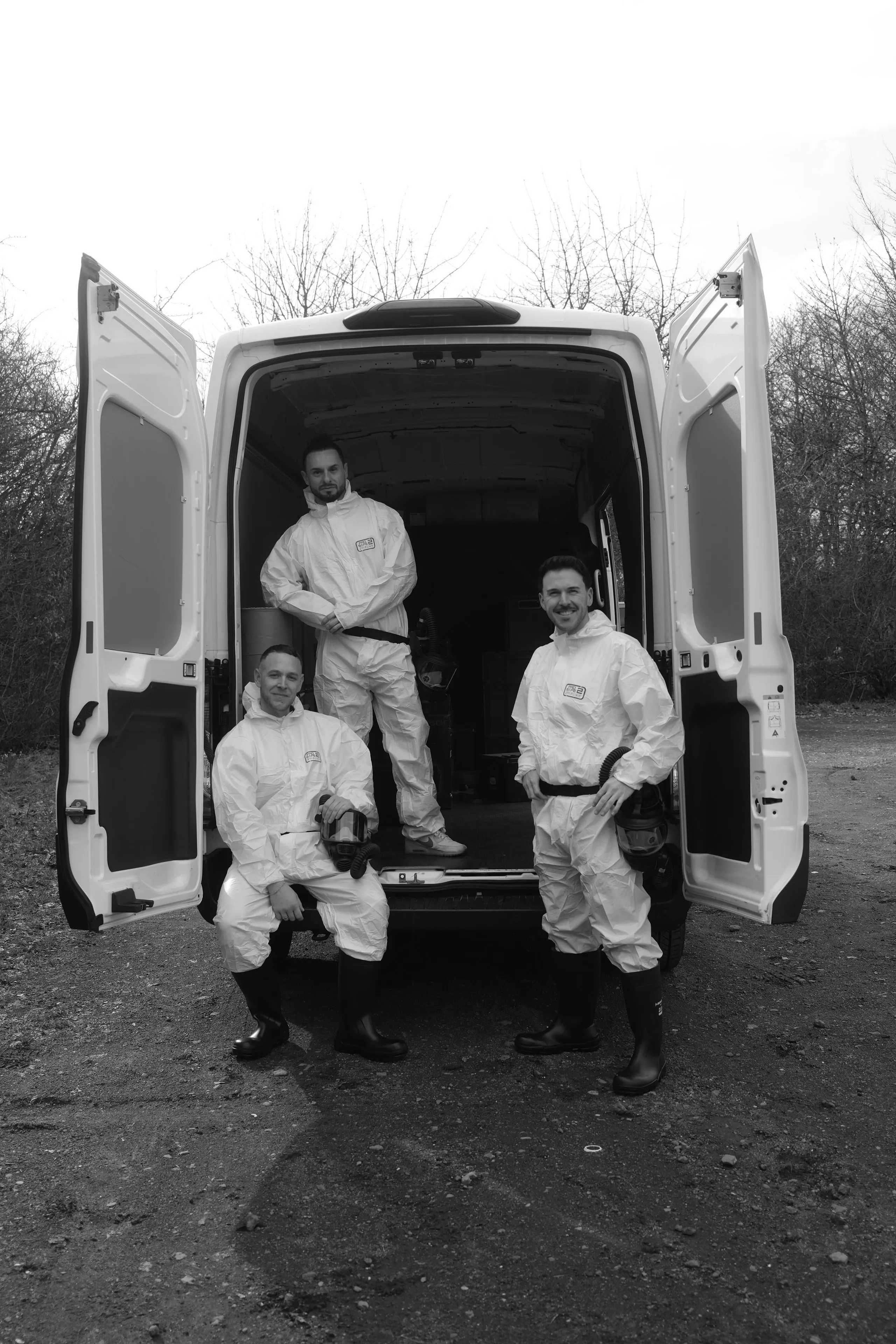 Team von Die Tatortreiniger Spezialisten in Schutzanzügen vor dem Einsatzfahrzeug für professionelle Tatortreinigung und Spezialreinigung.