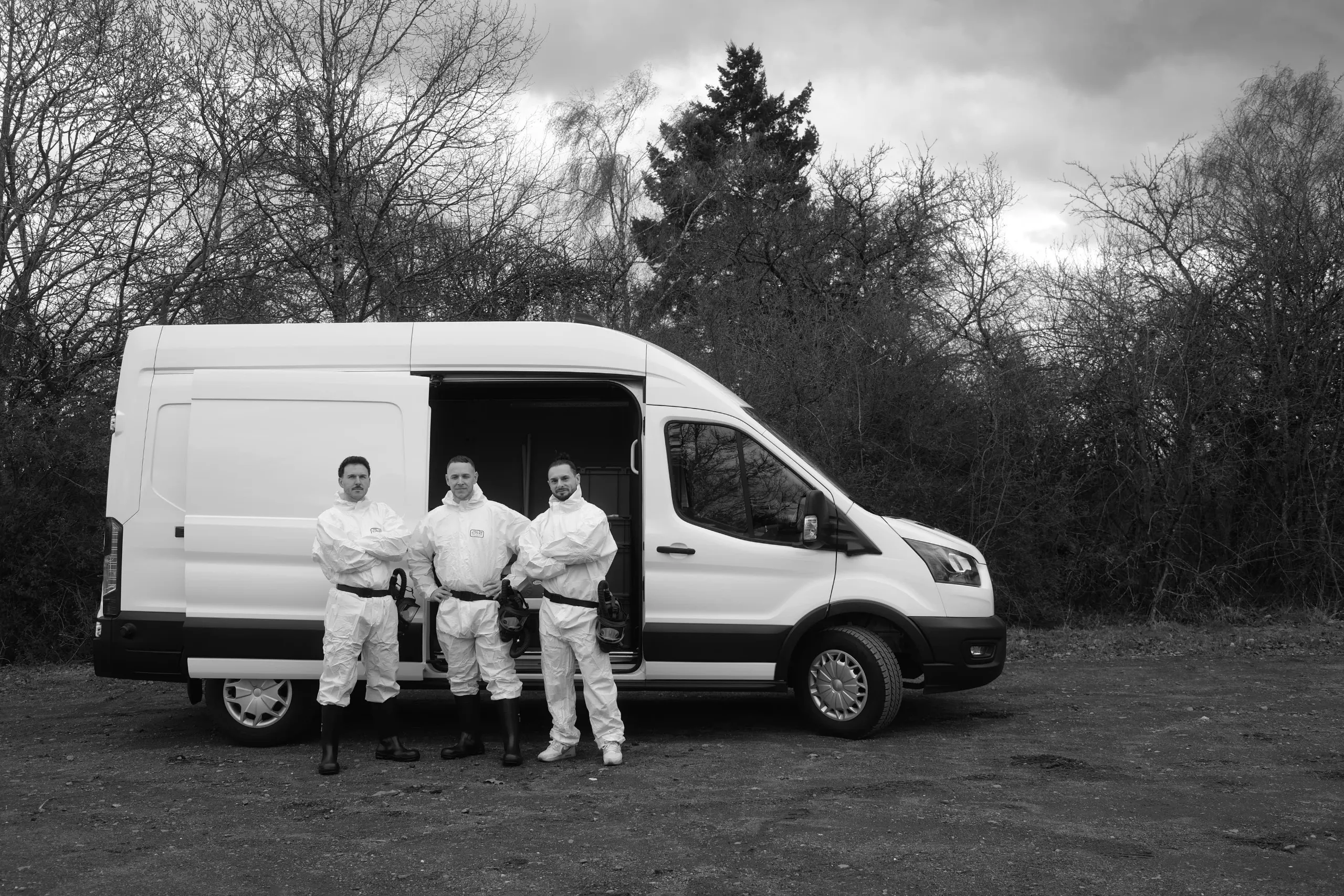 Team von Die Tatortreiniger Spezialisten in Schutzanzügen vor dem Einsatzfahrzeug für professionelle Tatortreinigung und Spezialreinigung.
