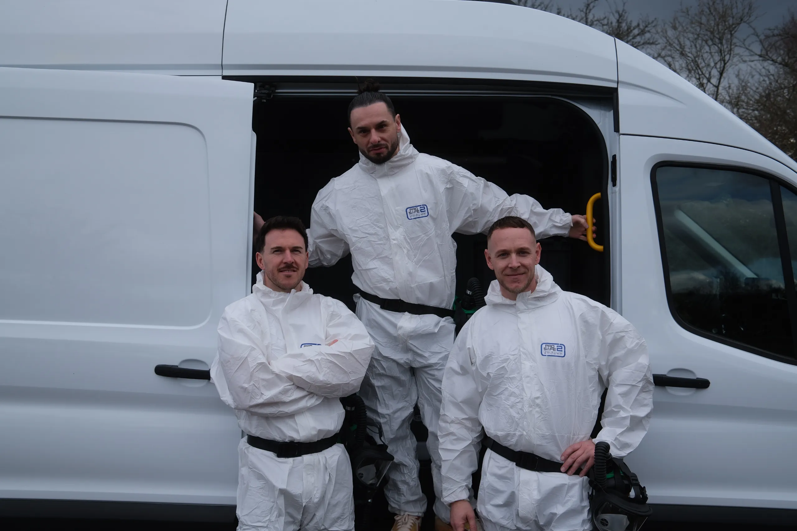 Team von Die Tatortreiniger Spezialisten in Schutzanzügen vor dem Einsatzfahrzeug für professionelle Tatortreinigung und Spezialreinigung.