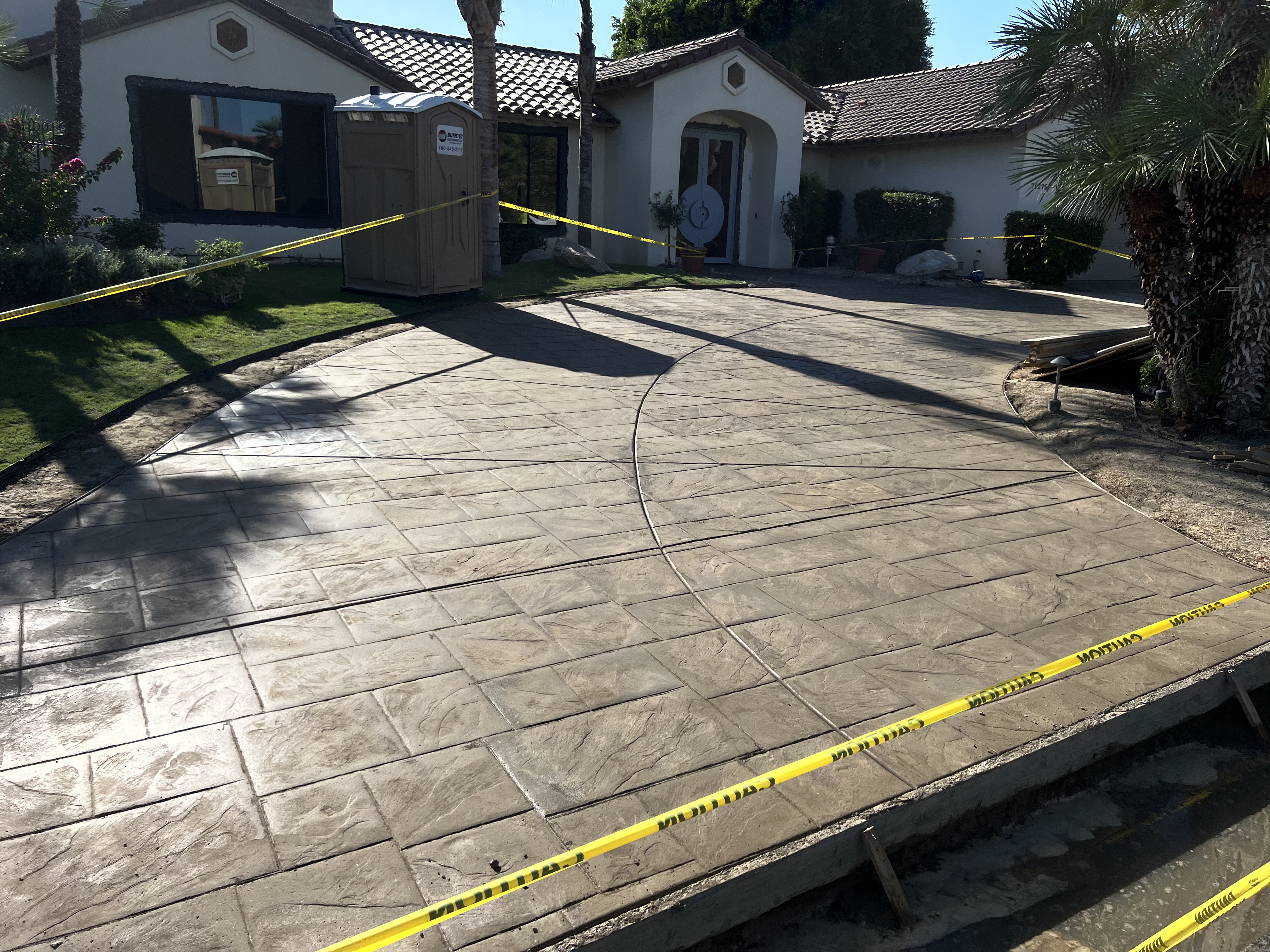 Curved stamped concrete driveway with textured surface and expansion joints.