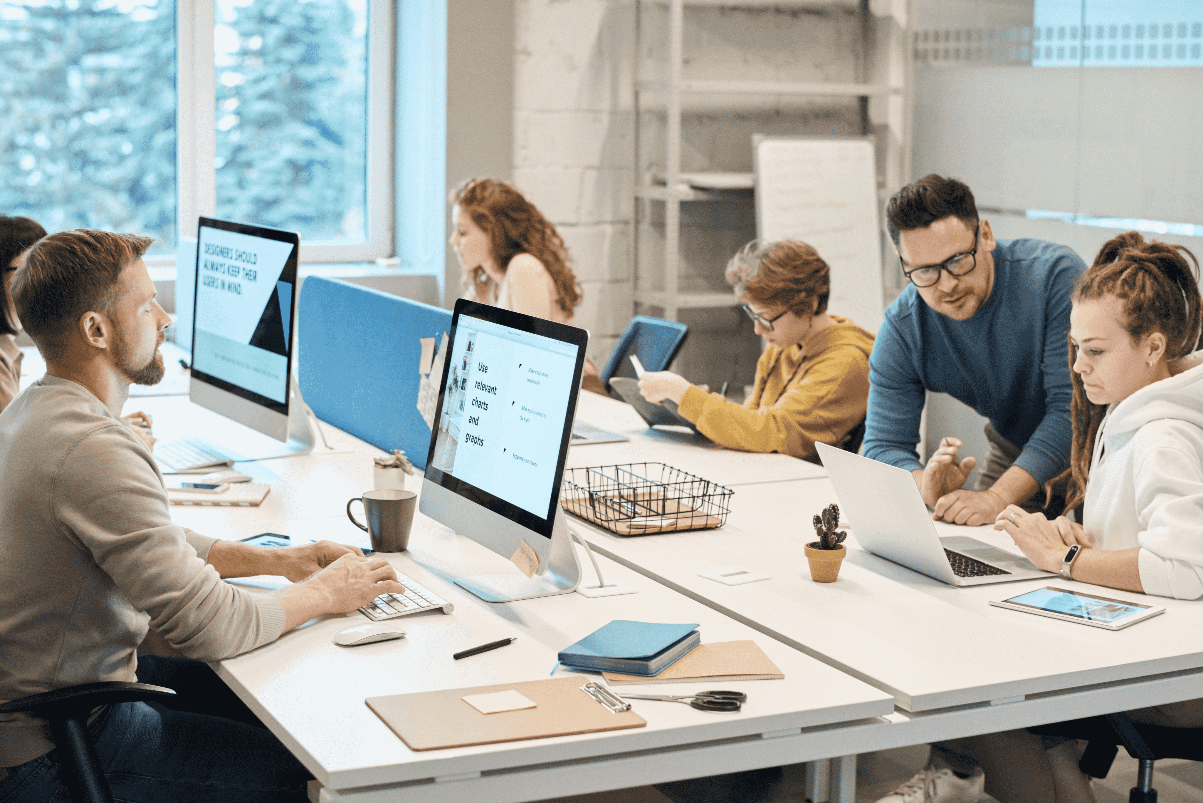 A group of people sitting at a table working on computers.