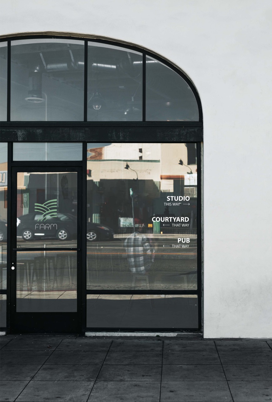 Modern storefront at Farm, glass showing directional signage for studio, courtyard, and pub.