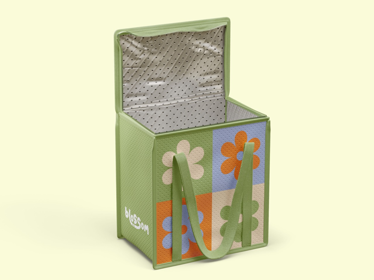 Open green lunch bag with colorful flower designs on the front panels.