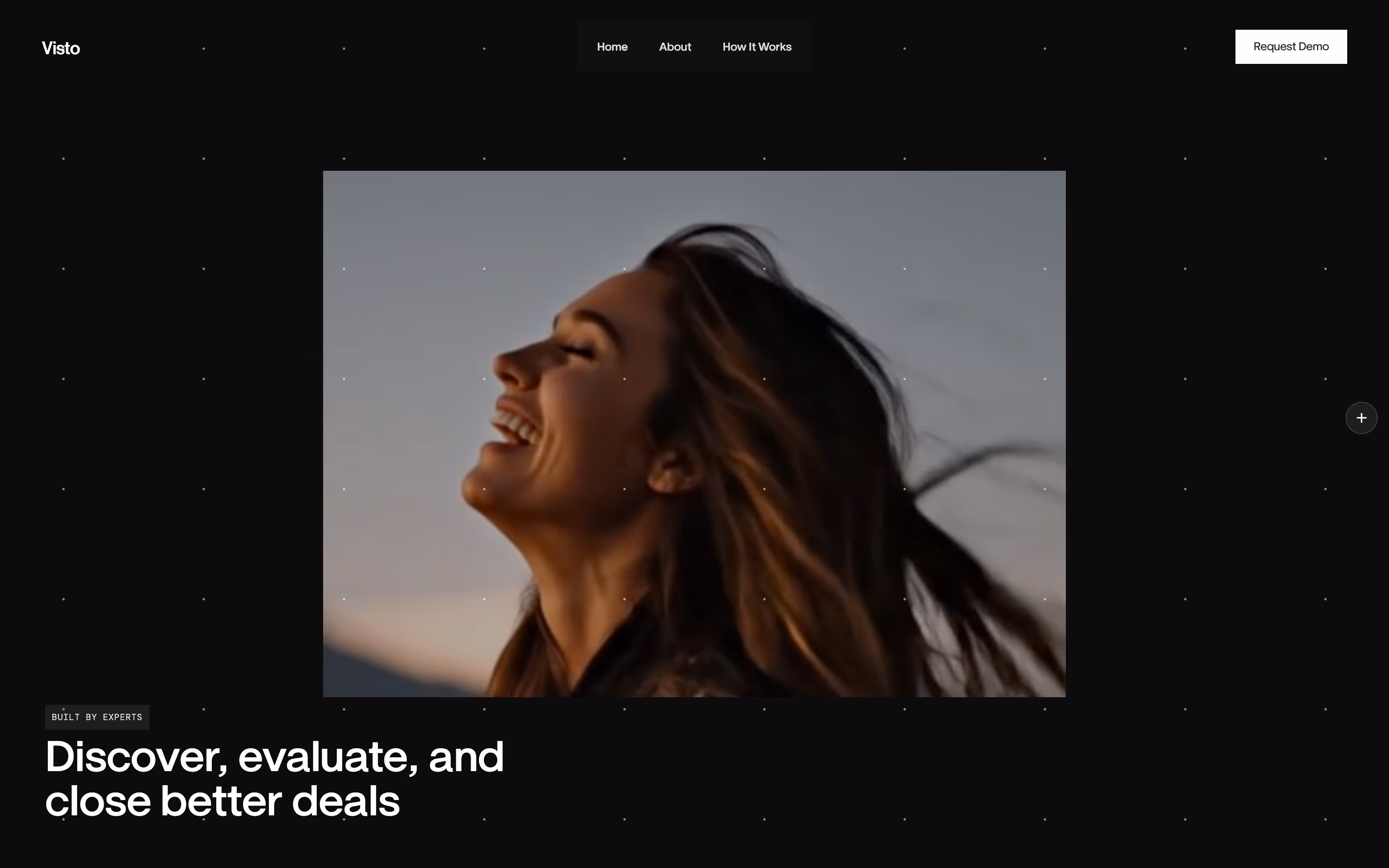 Side profile of a smiling woman with long hair blowing in the wind against a twilight sky.